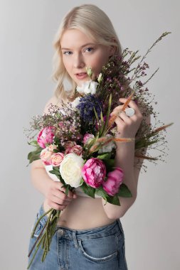 Çiçekleri tutan ve gülümseyen hoş bir genç kadın.