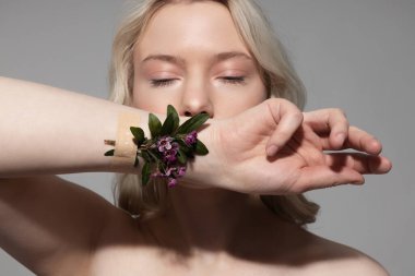 Çiçeklerle elini gösteren güzel genç bir kadın.