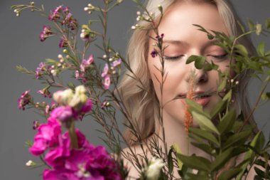 Güzel bitkilerin arkasında duran çekici genç bir kadın.