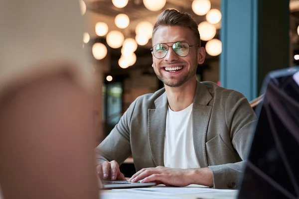 Enthousiaste jeune homme d'affaires souriant sur son lieu de travail — Photo