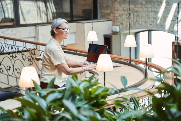 Stijlvolle zakenvrouw in bril chatten met collega 's tijdens het surfen internet — Stockfoto
