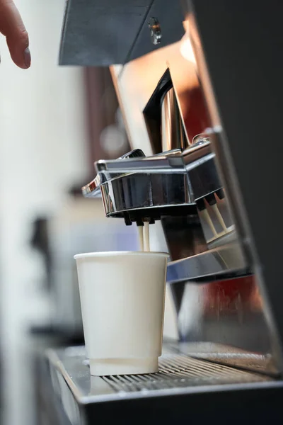 Λευκό χάρτινο φλιτζάνι καφέ στέκεται στην επαγγελματική καφετιέρα — Φωτογραφία Αρχείου