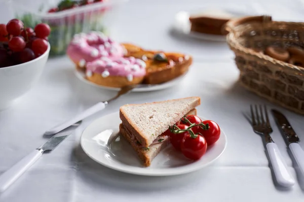 Leckeres Sandwich und Tomaten auf weißem Teller — Stockfoto