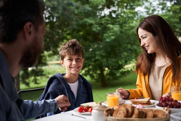 Liebevolle Eltern frühstücken mit niedlichem Sohn im Freien — Stockfoto