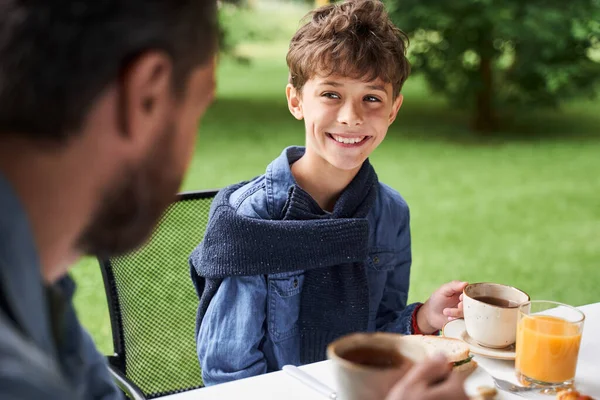 Veselý chlapec snídá s otcem venku — Stock fotografie