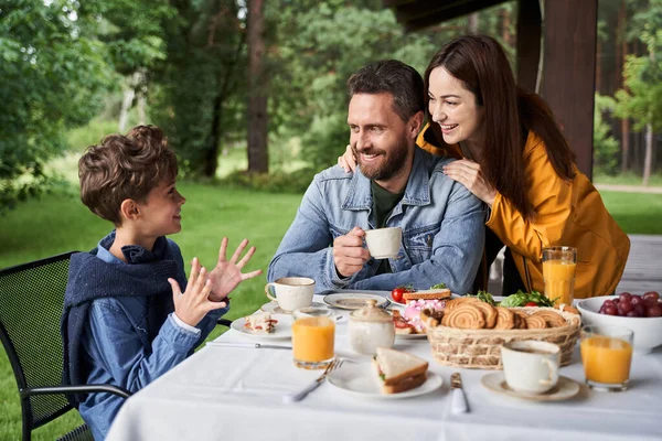 Glücklich liebende Eltern frühstücken mit Sohn im Freien — Stockfoto