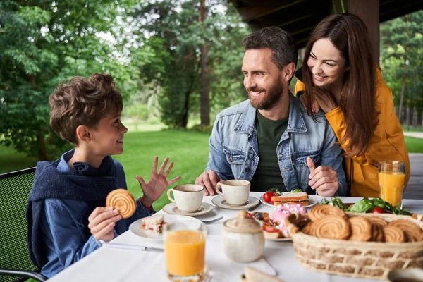 Glückliche Eltern plaudern mit Sohn beim Frühstück im Freien — Stockfoto