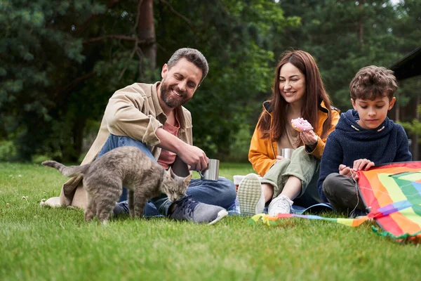 Happy family and cute cat having picnic outdoors — Stock Photo, Image