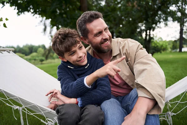 Cheerful father and son sitting on hammock swing outdoors — Stock Photo, Image