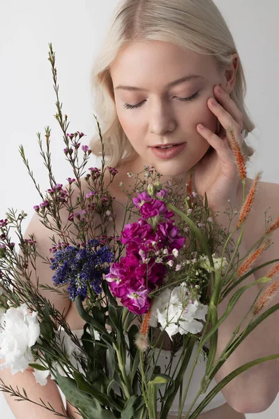 Bájos fiatal nő csukott szemmel, virágokkal a kezében — Stock Fotó