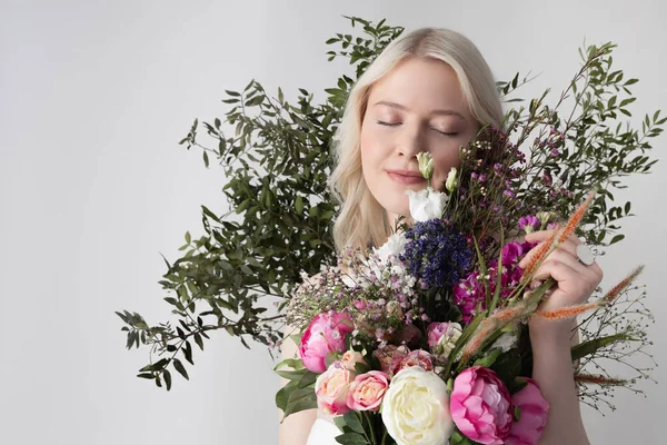 Charmante jonge vrouw met bloemen poseren tegen witte achtergrond — Stockfoto