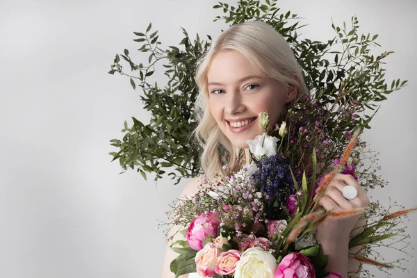 Щаслива молода жінка з квітами, що стоять на білому тлі — стокове фото