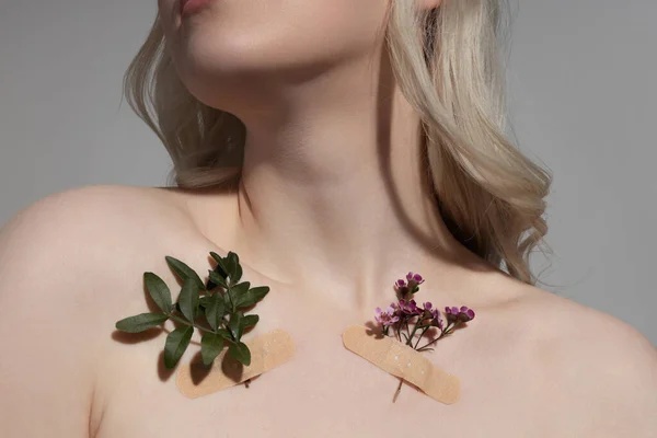 Jonge vrouw met planten op haar huid staan tegen grijze achtergrond — Stockfoto