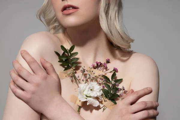 Blond dame met planten op haar huid staan tegen grijze achtergrond — Stockfoto