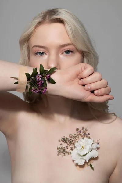 Hezká dáma s květinami na její kůži stojí proti šedému pozadí — Stock fotografie