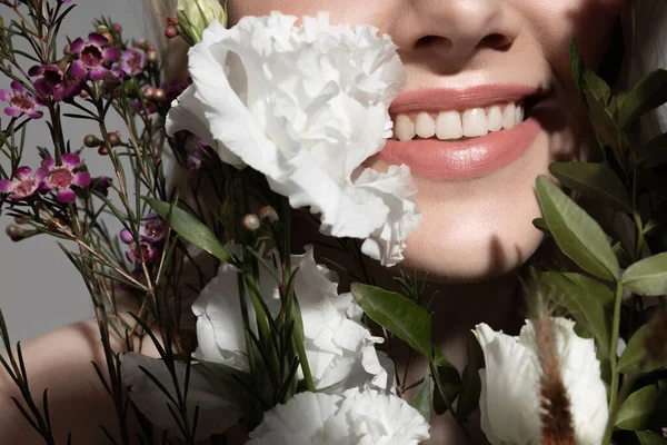 Jonge vrouw met charmante glimlach en kleurrijke bloeiende planten — Stockfoto