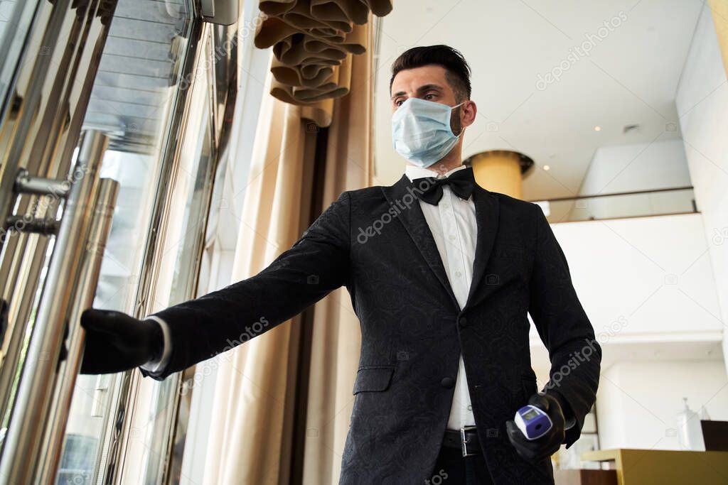 Young hotel receptionist working in medical mask and rubber gloves