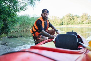 Kumlu sahilde kanonun yanında oturan yakın çekim adamı.