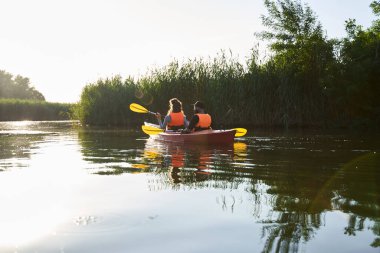 Akşamları nehirde kayak yapan çiftin yan görüntüsü