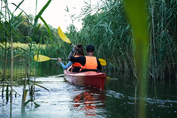 Kvinnliga och manliga vänner paddlar kajak på floden — Stockfoto