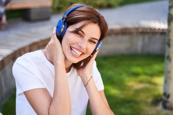 Mujer riendo y tomándose de la mano en los auriculares — Foto de Stock
