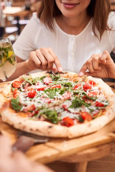 Vrouw die een stuk pizza eet in cafe — Stockfoto