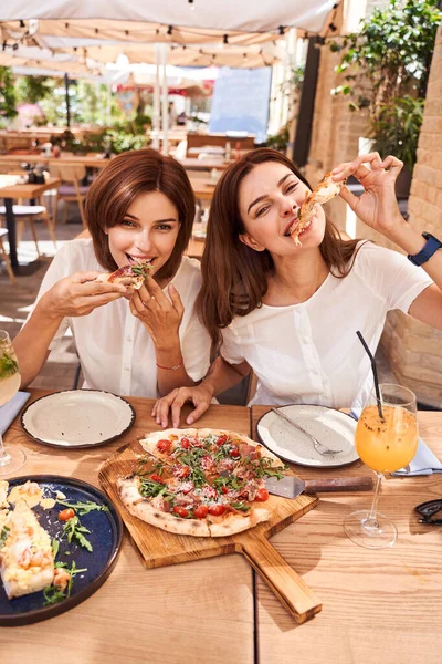 Smiling women eating pizza