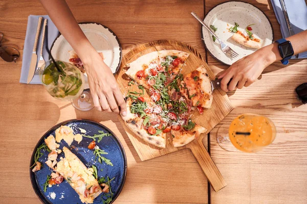 Hands grabbing vegetarian pizza