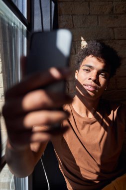 Pencerenin yanında selfie çeken bir adam.