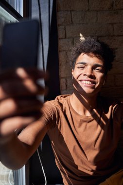 Pencerenin yanında selfie çeken bir adam.