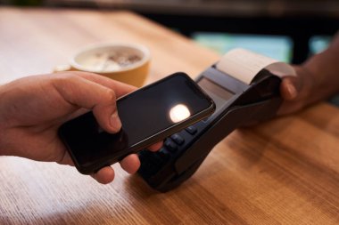 Müşteri cep telefonunu NFC teknolojisinin ödemesi için kullanıyor