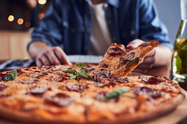 Sakallı bir adam kafede pizza yiyor.