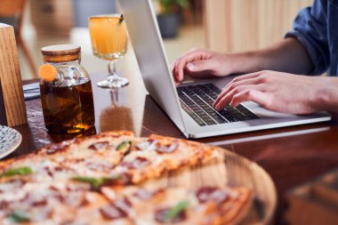 Bilgisayarda çalışan ve iş yerinde pizza yiyen adamı kapat.