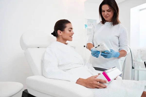 Kosmetikerin zeigt ihrer Patientin Spritze — Stockfoto
