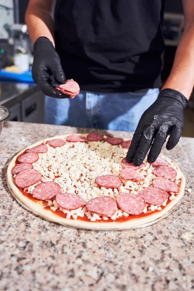 Homem adicionando ingredientes na massa — Fotografia de Stock