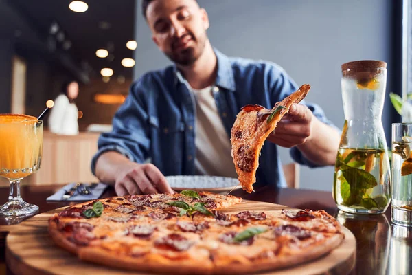 Low angle shot kerel met baard eten pizza in cafe — Stockfoto