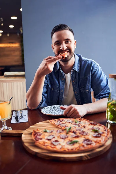 Man met baard die pizza eet in café — Stockfoto