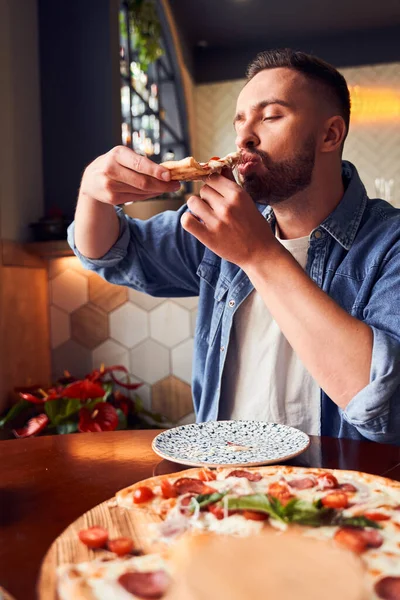 髭を生やした男がおいしいピザを食べる — ストック写真