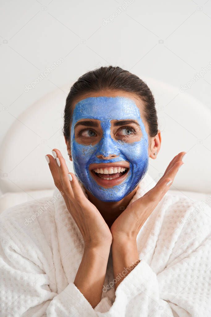 Woman in face mask of blue mud