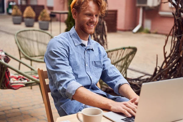 Jóképű férfi laptopon dolgozik a padon. — Stock Fotó