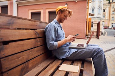 Bankta dizüstü bilgisayarda çalışan adamın kırpılmış görüntüsü.