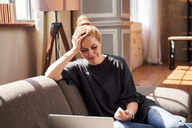 Evdeki dizüstü bilgisayarın önünde ağlayan üzgün kadın.