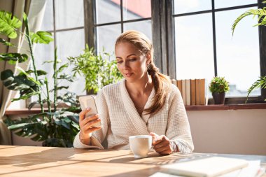 Güzel bir kadın sabah kahvesini evde içiyor.