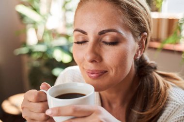 Hayalperest kadın en sevdiği sıcak içeceği kapalı gözlerle kokluyor.