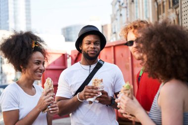 Dışarıda sosisli yiyen dört mutlu insan.