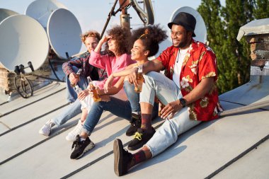 Şehrin çatısında bira içen mutlu gençler