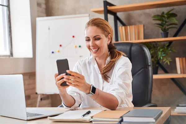 Mirthful dama teniendo videollamada en el trabajo y sonriendo — Foto de Stock