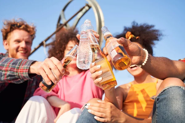 Szczęśliwi przyjaciele brzęczą butelkami napojów na świeżym powietrzu — Zdjęcie stockowe