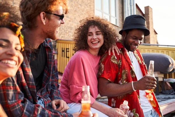 Fröhliche junge Leute trinken Bier bei Sonnenuntergang — Stockfoto