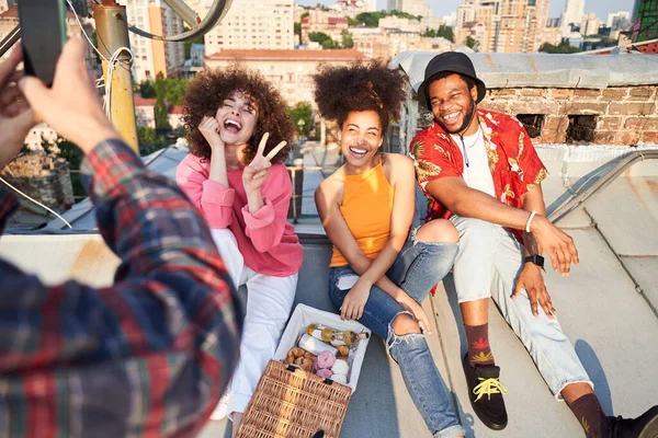 Chico tomando fotos de amigos alegres en el techo urbano —  Fotos de Stock